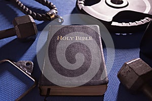 Bible Surrounded by Various Gym Equipment