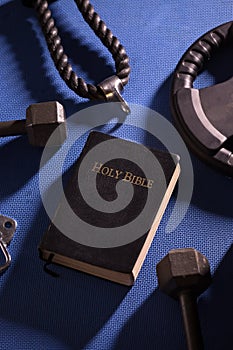 Bible Surrounded by Various Gym Equipment