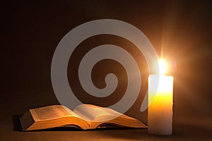 A bible on the table in the light of a candle