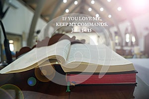 Bible verse quote - If you love me, keep my commands. John 14:15 on background of open page of bible book and light in the church