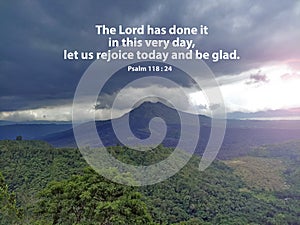 Bible verse quote - The Lord has done it in this very day, let us rejoice today and be glad. Psalm 118:24 on mountain background.