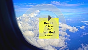 Bible verse quote Psalm 46:10 - Be still, and know that I am God. Spiritual sign of yellow notepaper on flight window.