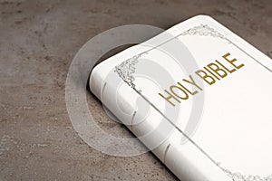 Bible with white cover on light grey table, closeup