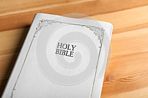 Bible with white cover on wooden table, closeup