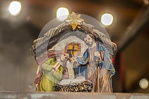 Biblical Mary and Joseph look down on Baby Jesus in the manger in a Christmas nativity scene against bokeh background