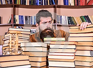 Bibliophile concept. Teacher or student with beard sits at table with books, defocused. Man on hopeful face between