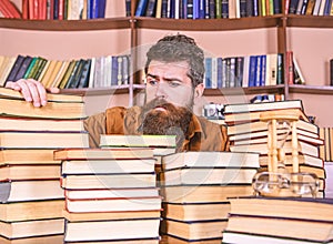 Bibliophile concept. Teacher or student with beard sits at table with books, defocused. Man on hopeful face between