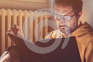 Bibliophile mid-adult male reading a book at home, closeup headshot portrait