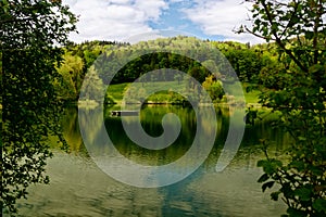 Bichelsee in spring at noon, photographed from the shore overlooking the lake, empty swimming platform in front of a beautiful