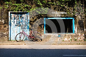 Bicicle in front of a abandoned building with blue door and window, Kochi, Kerala, India