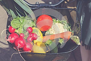 Bicycle basket filled with fresh vegetables from marketplace.