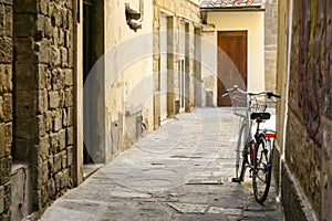 A bicycle with a basket on a narrow European street. Stone houses.