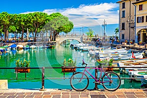 Bicycle bike near fence of old harbour Porto Vecchio with motor boats on turquoise water photo