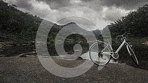 Bicycle on the bridge cross over river when heavy raining day