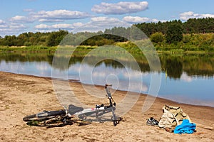 Bicycle camping on the river beach. Hot summer day for swim, nature landscape and reflections in the water