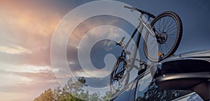 Bicycle on the car roof rack against sunset sky. copy space