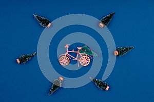 Bicycle with Christmas tree surrounded by snowed trees on classic blue