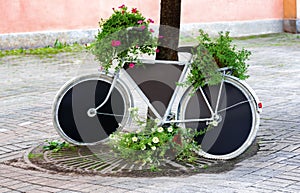 A bicycle converted into a flowerbed, and a billboard. Decor, flowers in pots. Beautiful photography.