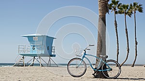 Bicycle cruiser bike by ocean beach, California coast USA. Summer cycle, lifeguard hut and palm tree