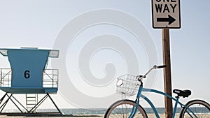 Bicycle cruiser bike by ocean beach, California coast USA. Summer cycle, lifeguard tower, road sign