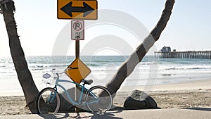 Bicycle cruiser bike by ocean beach, California coast USA. Summer cycle, road sign, waves and pier.