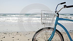 Bicycle cruiser bike by ocean beach California coast USA. Summertime blue cycle, sand and water wave