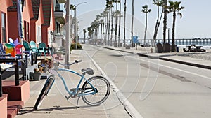 Bicycle cruiser bike by ocean beach, California coast USA. Summertime cycle, cottages and palm tree.