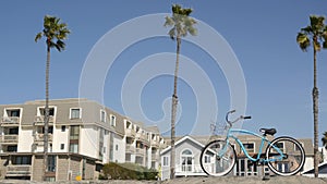 Bicycle cruiser bike by ocean beach, California coast USA. Summertime cycle, houses and palm trees.