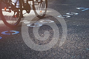 bicycle driving over modern bicycle route symbols painted in blue color on asphalt.