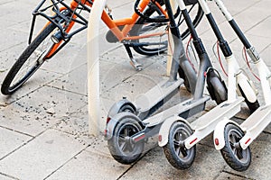 Bicycle and electric scooters parked on city street. Self-service street transport rental service. Rent urban vehicle with photo