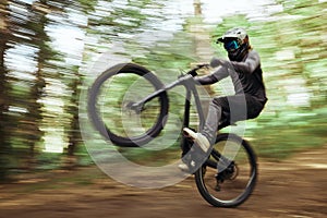 Bicycle, forest and man wheelie, fast and workout outdoor in woods for healthy body. Mountain bike, nature or athlete