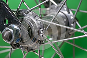 bicycle front wheel hub with spokes fitting detail on green background.