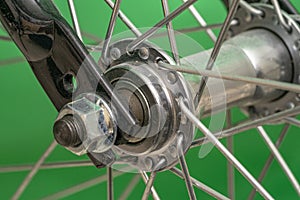 bicycle front wheel hub with spokes fitting detail on green background.