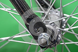 bicycle front wheel hub with spokes fitting detail on green background.