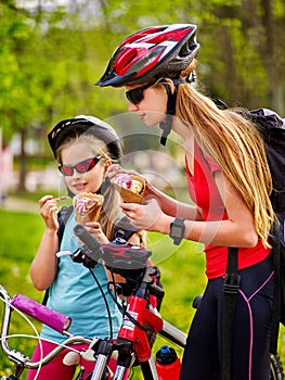 Bicycle girls with rucksack eating ice cream cone in park.