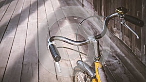 Bicycle handle bar close up. Vintage filter. wooden floor background