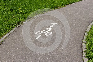 Bicycle icon, background wallpaper. Cyclist sign on asphalt bicycle way with grass on the sides