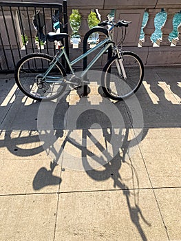 Bicycle and its shadow, as it leans against bike holder in Chicago Loop during summer photo