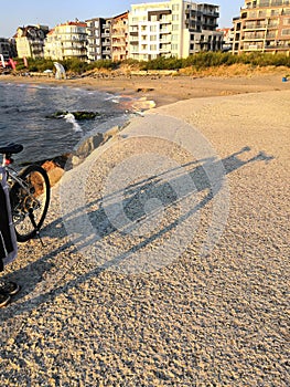 Bicycle and its shadow on the beach. Black bicycle with a lock chain waiting on a sunny summer day