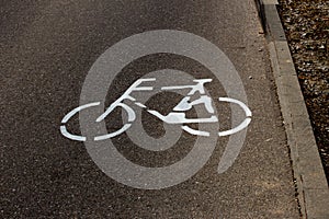 Bicycle lane symbol painted on a road next to a curb