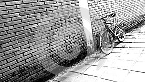 bicycle leaning against brick wall.  the photo is in black and white.  suitable for use as a content background