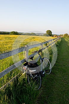 A bicycle leaning against a wooden fence next to a field