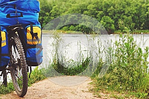 Bicycle with luggage stopped near precipitous shore of the river.