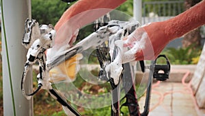 Bicycle maintenance. Bike mechanic cleaning bike with soap foam and washcloth on backyard of repair shop. Man washing his road bic