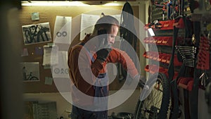 Bicycle maintenance. Bike mechanic talking with colleague on smartphone. Rider is wiping the bike clean working in