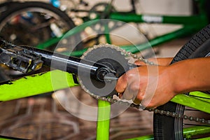 Bicycle mechanic adjusting the bicycle pedal in a workshop in the repair process, in a blurred background