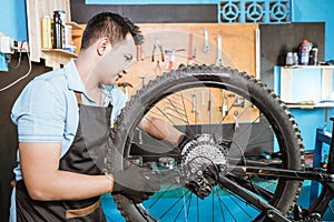 a bicycle mechanic in apron installs axles when installing bicycle wheels