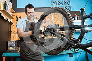 bicycle mechanic in aprons tightens spokes while fixing problems