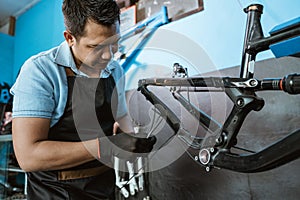 a bicycle mechanic attaches brake cables while assembling a bicycle frame