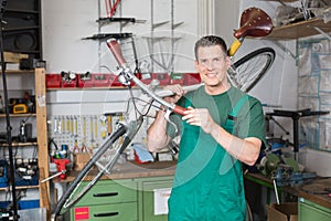 Bicycle mechanic carrying a bike in workshop